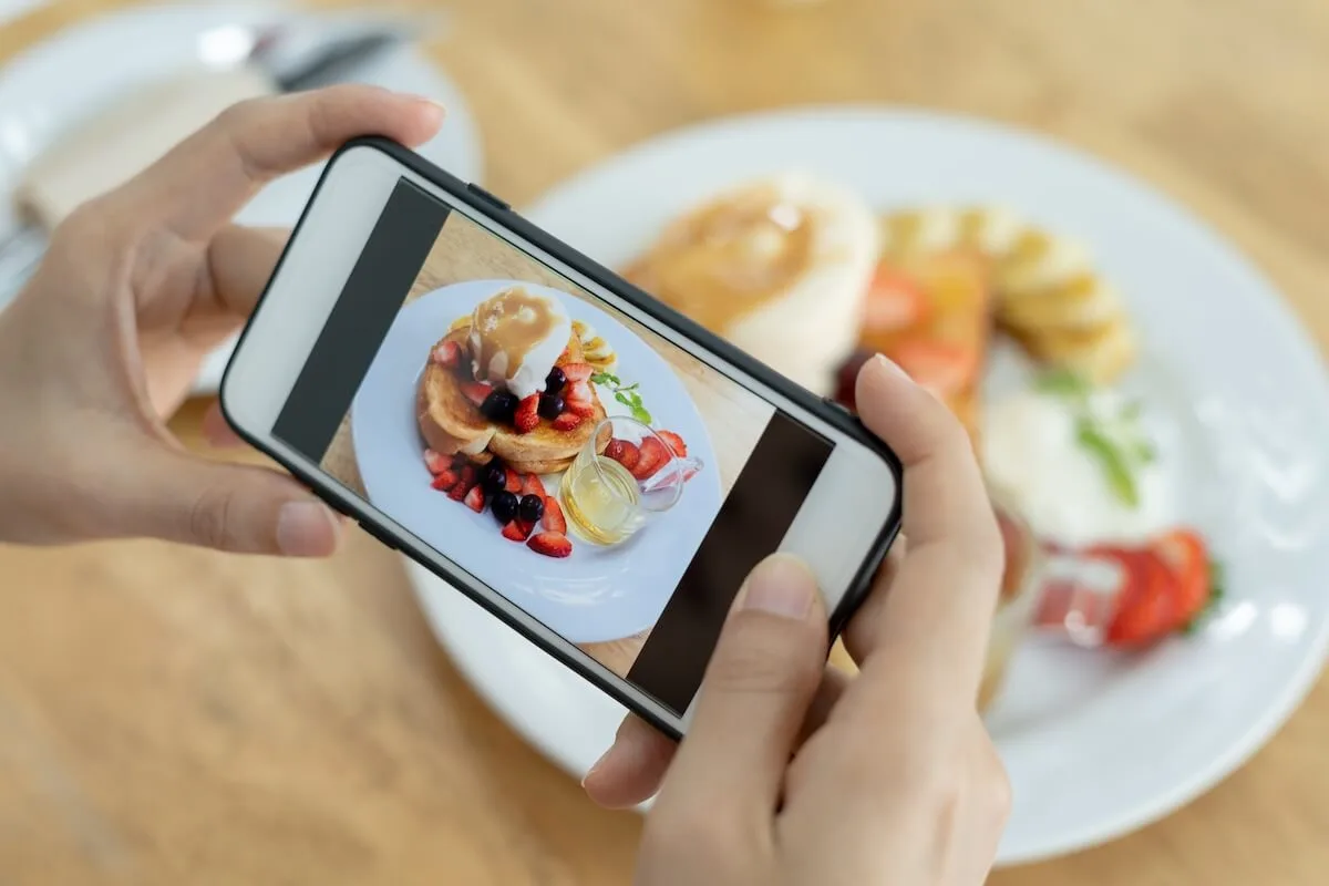 Increase restaurant reservations using social media: customer taking a picture of a dish