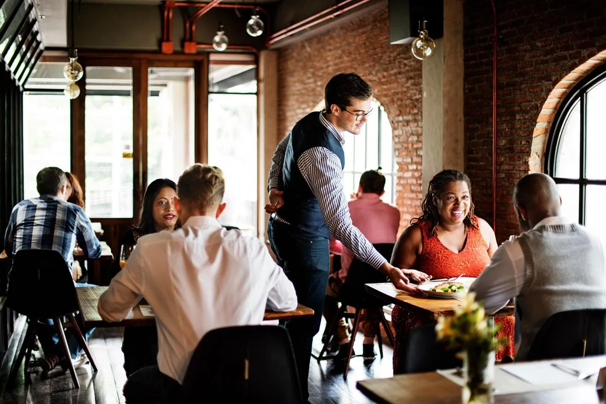 Diners sitting at tables inside a restaurant enjoying their meals.