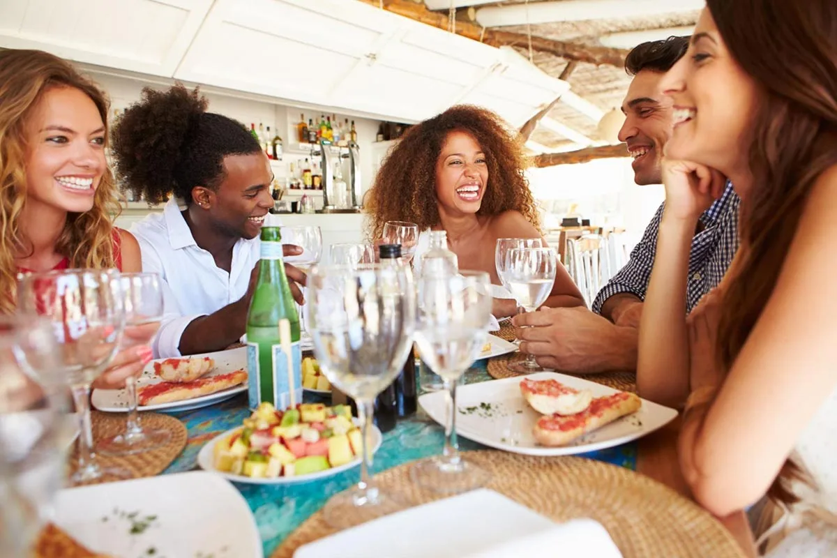 Group of friends eating and drinking together at a restaurant.