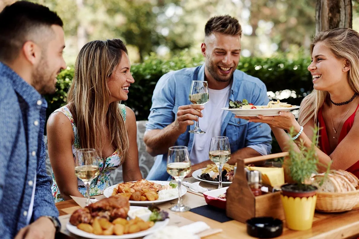 Group of friends dining at outdoor restaurant during summer.