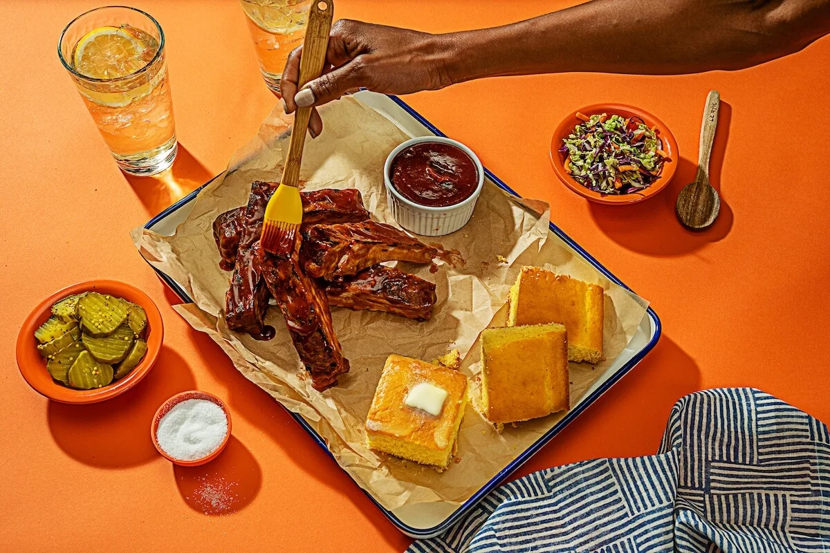 Restaurant social media marketing: person brushing sauce on grilled ribs