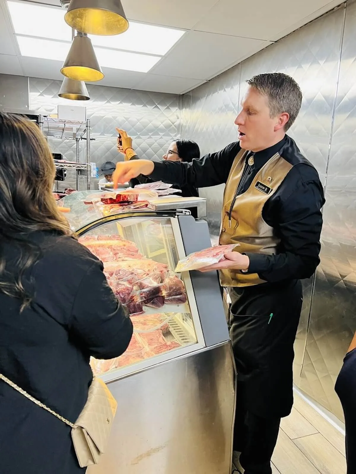 Server showing different kinds of meat to a customer