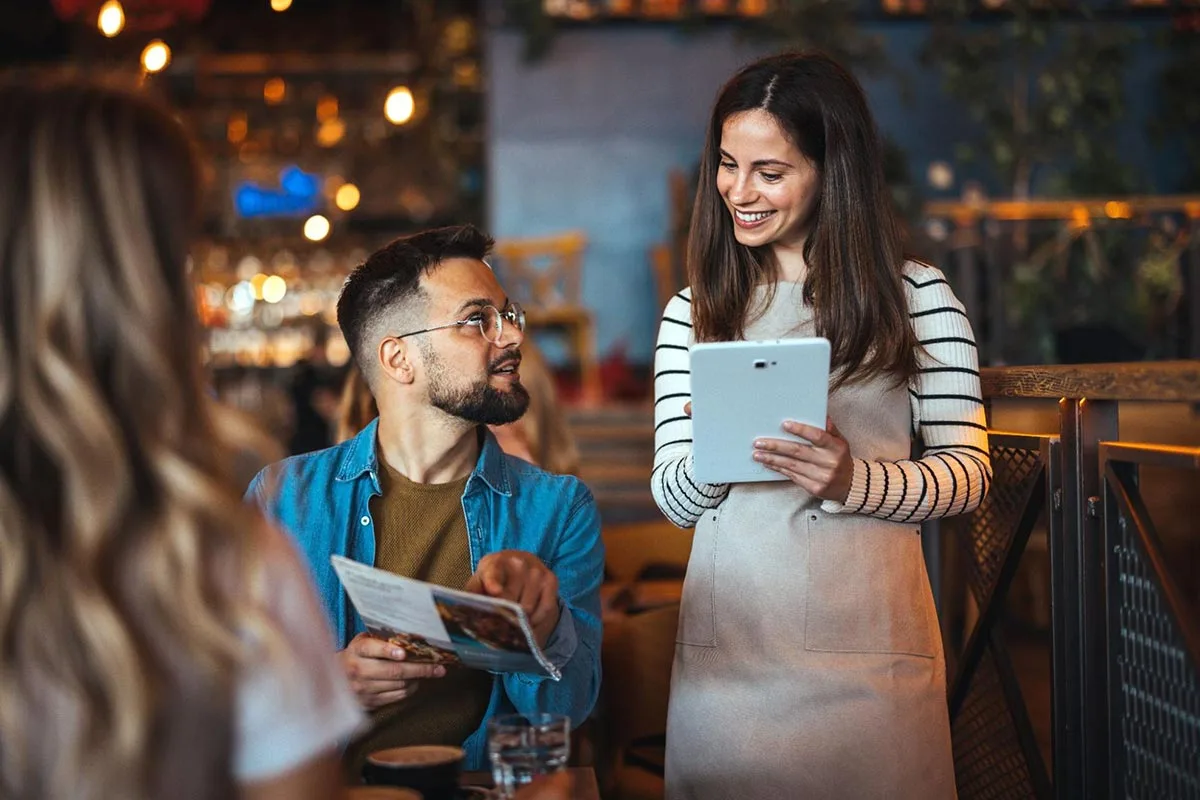 Restaurant server taking order from customer using digital tablet.
