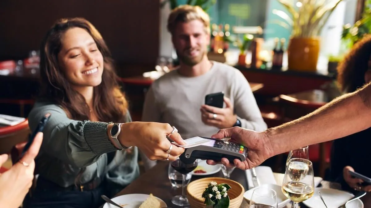Customer paying at restaurant by card at the table.