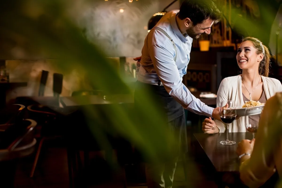 Online restaurant reservation system: waiter serving food to a customer
