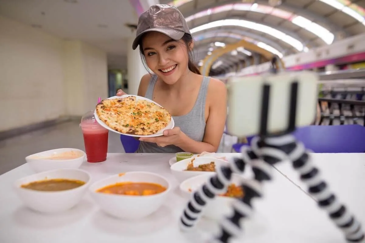 Influencer recording a video of herself eating at a restaurant