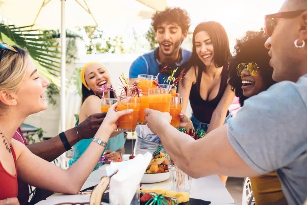 A group of friends toasting drinks together outdoors, enjoying a social gathering at restaurant.