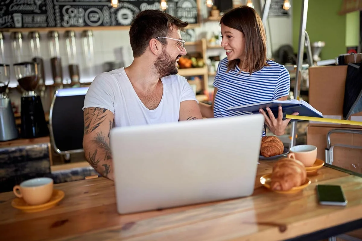 Restaurant owners using laptop to update yelp page at their restaurant.