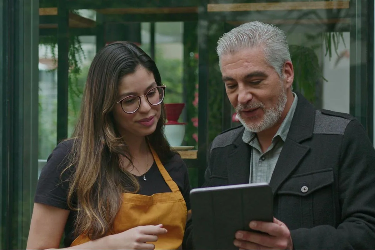 Restaurant server helping customer book table with tablet.