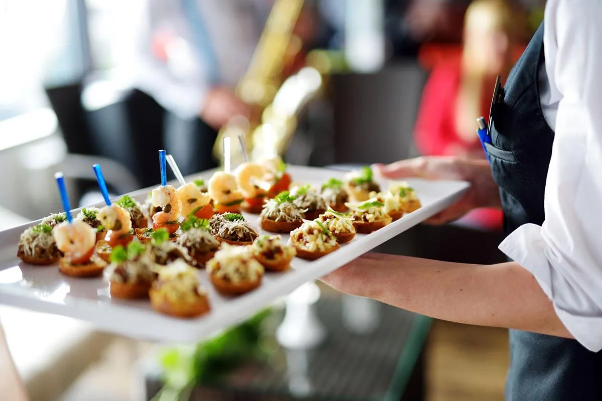 A server holding a tray of assorted canapés.