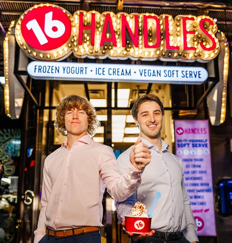 Photo of co-owner and CEO Neil Hershman and Co-Owner and Chief Creative Officer Danny Duncan posing outside a 16 Handles after the brand acquisition.
