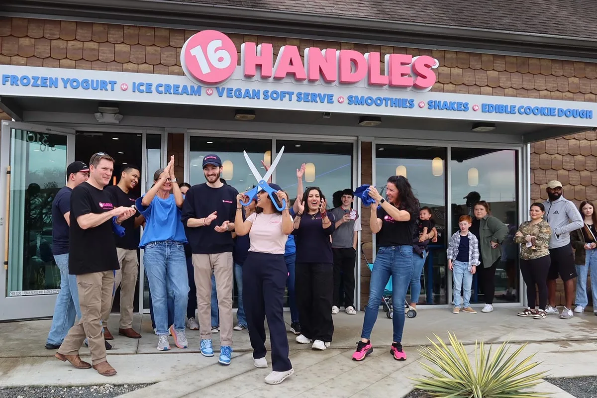 Photo of 16 Handles employees and customers celebrating the opening of a new location at a ribbon-cutting ceremony.