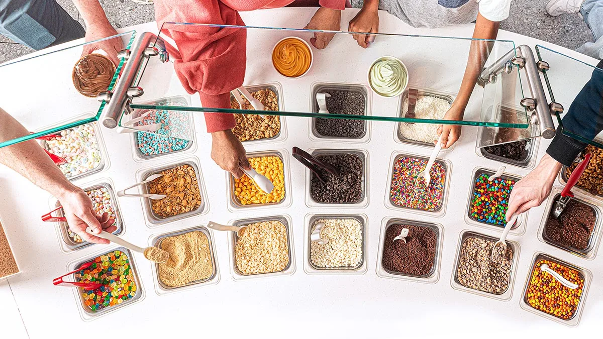 Photo of customers choosing toppings from the self-serve topping bar at 16 Handles.