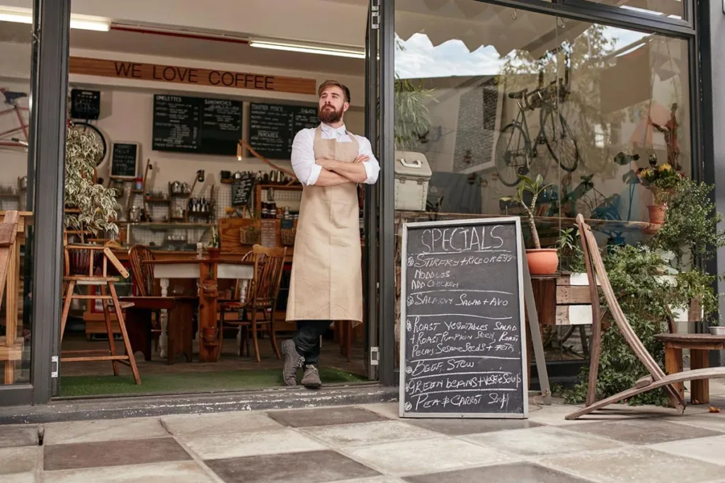 A bistro owner is standing next to a signage menu outside the restaurant.