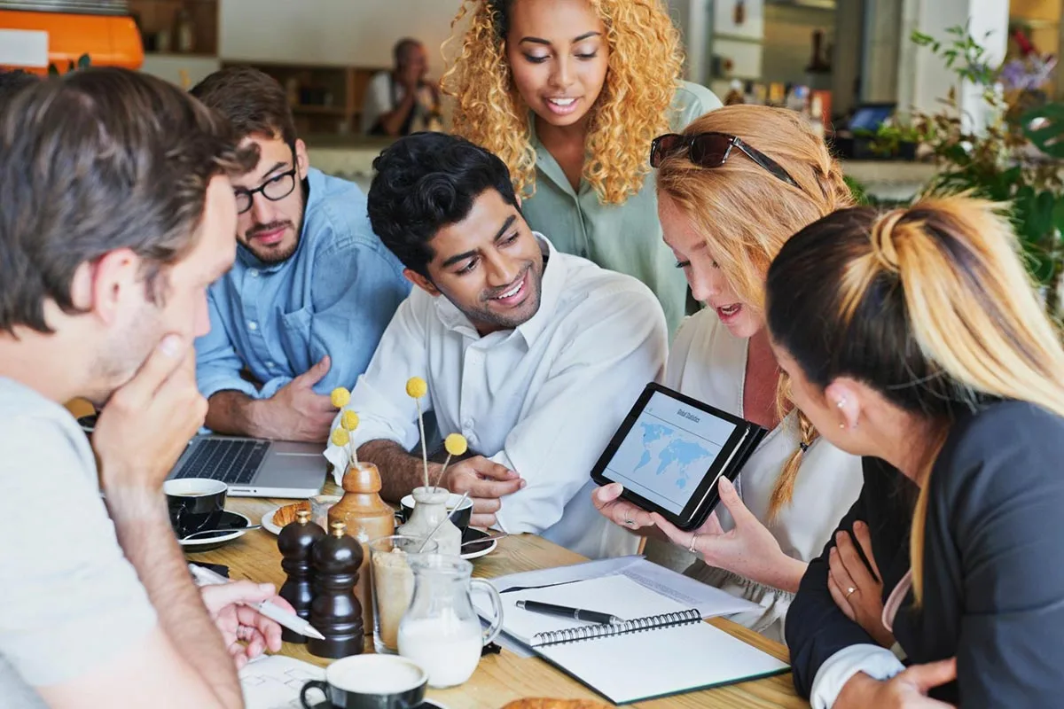 Social media marketing team gathered around a table brainstorming strategies and collaborating on digital marketing campaigns.