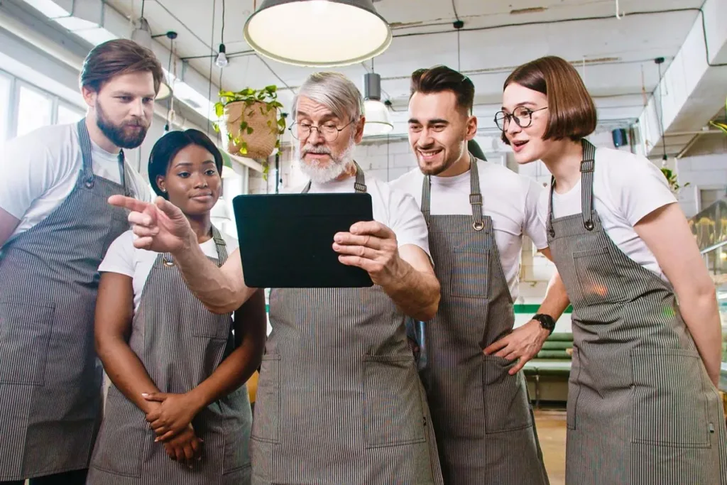 A restaurant team collaborates while using a laptop.