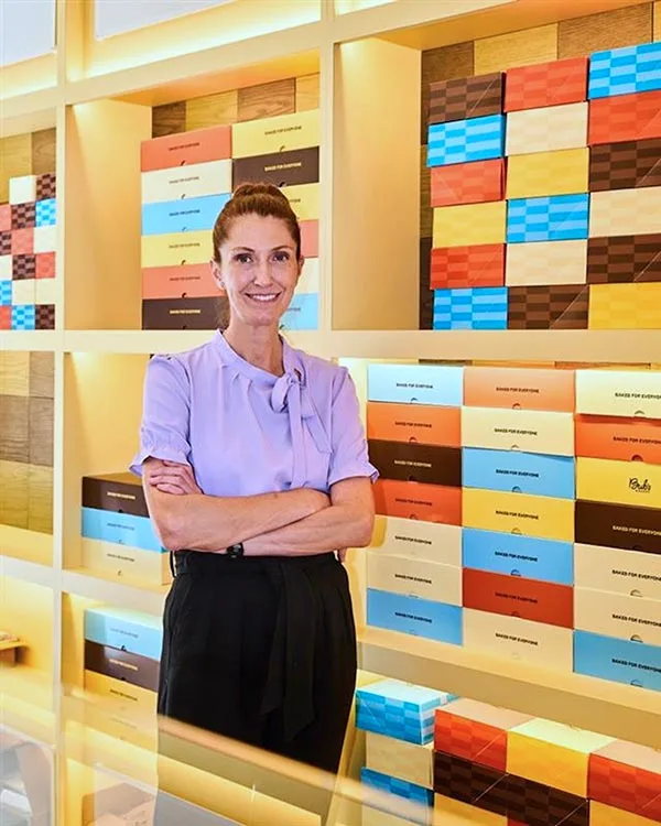 Photo of Bub's Bakery co-founder Melissa Weller standing in front of a row of to-go boxes from 55 Hospitality.