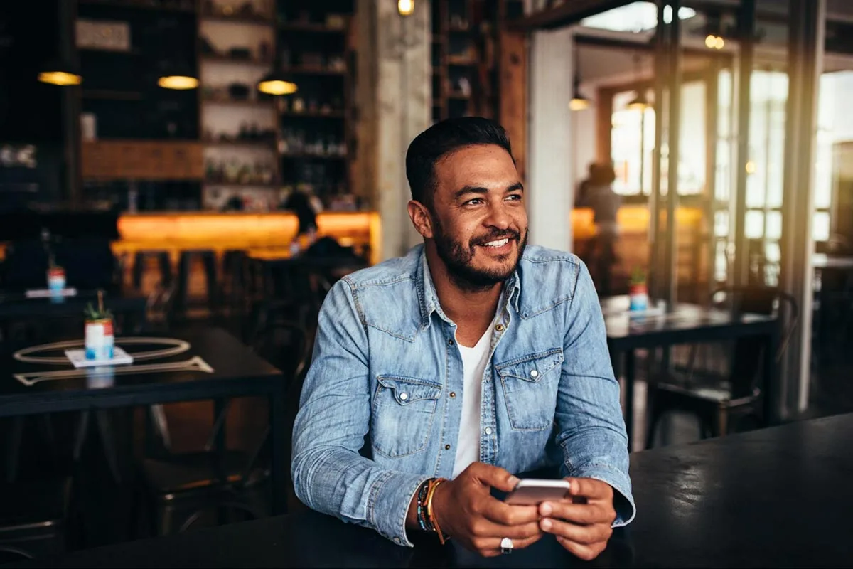 A restaurant customer smiles happily after finishing his meal.
