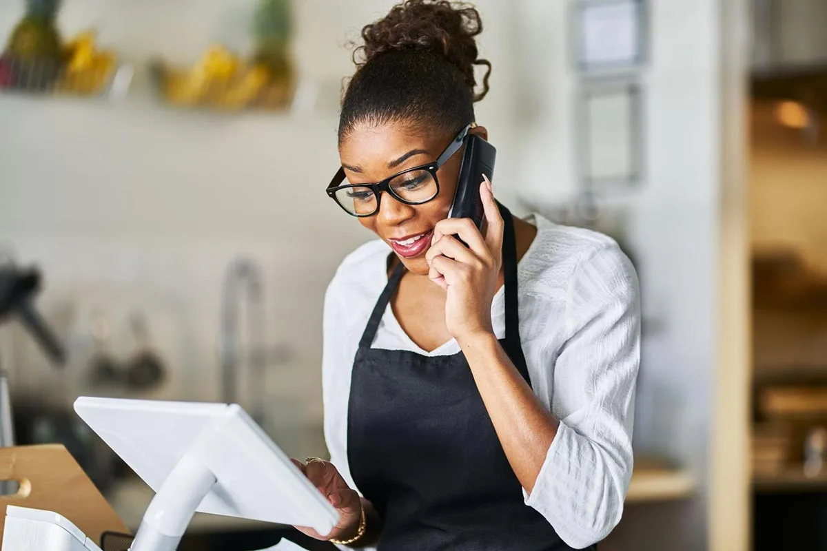 A restaurant manager is on the phone answering customer questions.