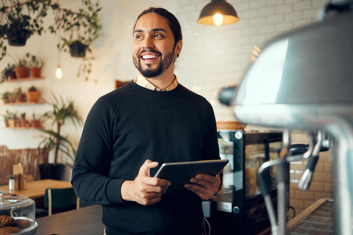 Restaurant manager smiling while holding a tablet device.