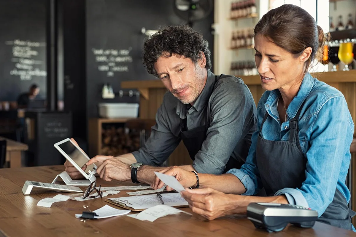 Restaurant managers using a calculator to analyze and manage inventory costs.